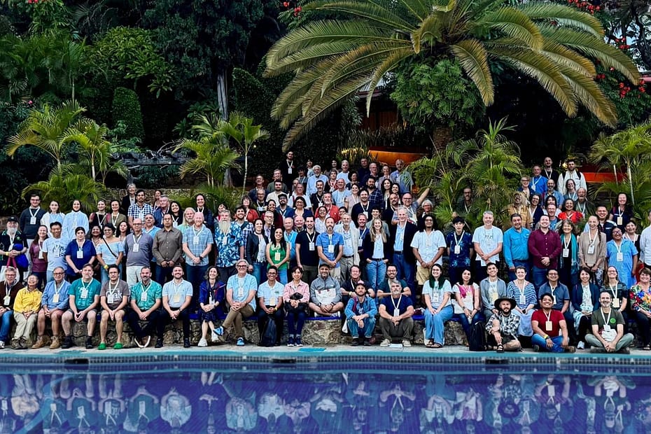 Attendees at the International Oak society conference Mexico 2025. A large group of people in front of palm trees, next to a swimming pool.